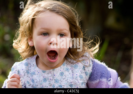 Ragazza giovane con entusiasmo corre attraverso il giardino Foto Stock