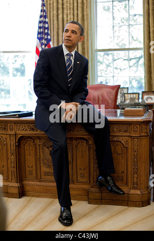 Il presidente Barack Obama si appoggia contro la risoluta scrivania in ufficio ovale Foto Stock