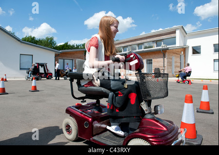 Una giovane ragazza disabili imparare a guidare uno scooter di mobilità in tutta sicurezza presso il Centro per gli studi sulla disabilità a Rochford, Essex, Regno Unito. Foto Stock