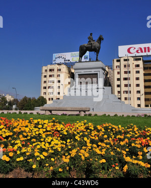 Cielo blu fiori di colore giallo verde erba vista generale Baquedano monumento, di fronte agli edifici, Plaza Baquedano, Santiago del Cile Foto Stock