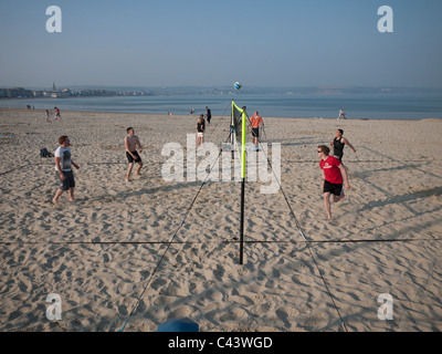 I giovani uomini a giocare pallavolo al sole del pomeriggio presso la spiaggia di Weymouth Dorset, Inghilterra Foto Stock