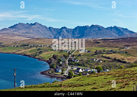 Vista da sopra il villaggio di Skye Carbost verso il Cuillin Hills con Talisker distilleria di whisky in primo piano. Foto Stock