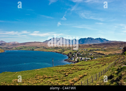 Vista da sopra il villaggio di Skye Carbost verso il Cuillin Hills con Talisker distilleria di whisky in primo piano. Foto Stock