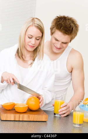 La colazione felice coppia giovane rendere il succo di arancia in cucina di mattina Foto Stock