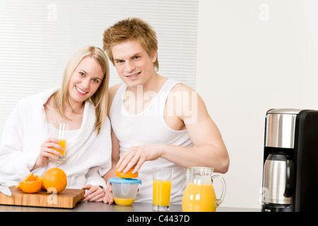 La colazione felice coppia giovane rendere il succo di arancia in cucina di mattina Foto Stock
