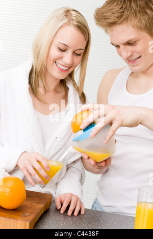 La colazione felice coppia fare il succo di arancia in cucina di mattina Foto Stock