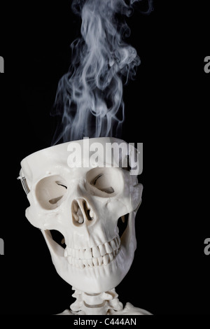 Uno scheletro con fumo che esce fuori dal suo cranio Foto Stock