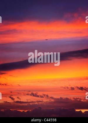 Un aeroplano che vola nel cielo come il sole tramonta Foto Stock