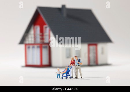 Una giovane famiglia di statuette in miniatura nella parte anteriore di una casa Foto Stock