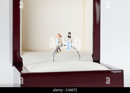 Statuine in miniatura di una famiglia giovane seduto su un anello di nozze in una scatola di gioielli Foto Stock