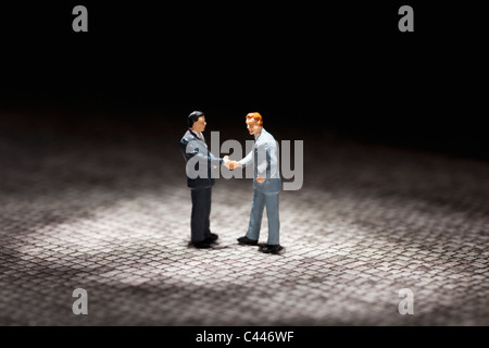 Due uomini di affari in miniatura figurine stringono le mani Foto Stock