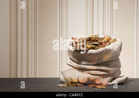 Grande sacco pieno di monete in euro su un tavolo Foto Stock