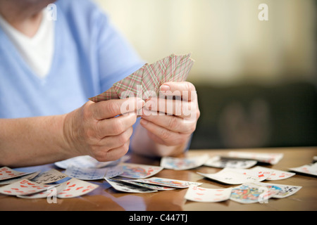 Un senior donna giocando a carte, sezione mediana, concentrarsi sulle mani Foto Stock