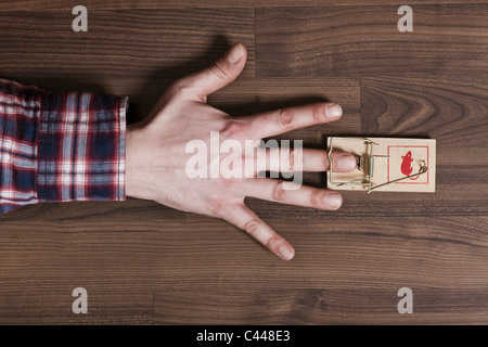 Un uomo del dito intrappolato in un mousetrap, close-up di mano Foto Stock