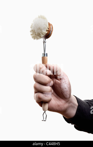 Un uomo con in mano una spazzola scrub con schiuma di sapone su di esso, close-up di mano Foto Stock