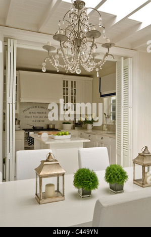 Bianco area da pranzo con lanterne e lampadario e vista attraverso alla cucina Foto Stock