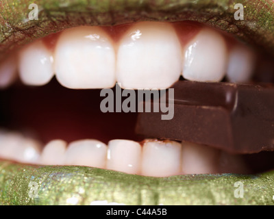 Una donna di mangiare un pezzo di cioccolato, extreme close up di bocca Foto Stock