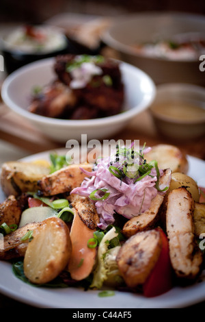 Un'insalata di pollo, comprendente di Spicchi di patate cavolo viola coleslaw, Cipolline e carote Foto Stock