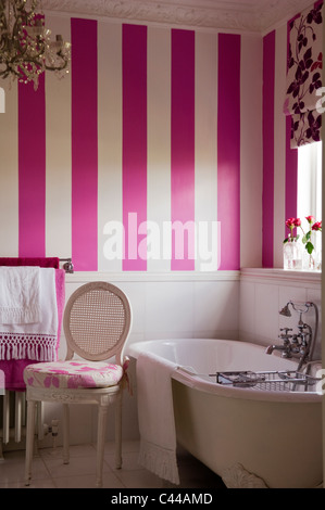 Freestanding vasca nel bagno con carta da parati a strisce e tende dai motivi floreali Foto Stock