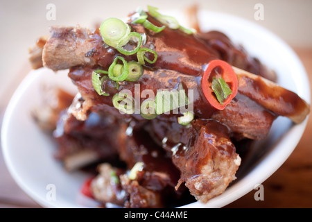 Un piatto gourmet di appiccicoso stile cinese costine servita con il peperoncino, zenzero e cipolline Foto Stock