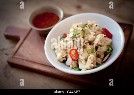 Un piatto di fritti e martoriata calamari calamari, servita con peperoncino, Zenzero cipolline e peperoncino dolce salsa di immersione Foto Stock