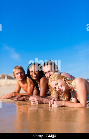 Il gruppo di quattro amici - uomini e donne - sulla spiaggia avente un sacco di divertimento nella loro vacanza Foto Stock