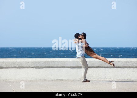 Euforico coppia giovane incontro abbracciando e vicino al mare. Sagoma orizzontale, vista laterale, spazio di copia Foto Stock