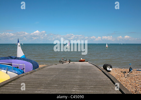 Regno Unito, Inghilterra, Kent, Whitstable, Molo sulla spiaggia con barche a vela in background Foto Stock