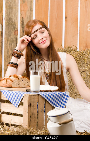 Redhead giovane donna hippie hanno la colazione sul fieno nel fienile Foto Stock