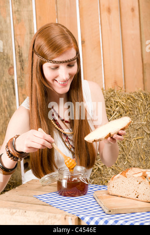 Giovani red-capelli donna hippie hanno prima colazione biologica nel fienile Foto Stock