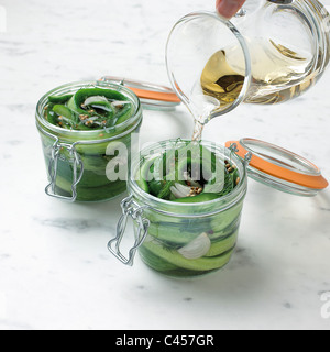 Versare aceto su cetriolo in vasi, close-up Foto Stock