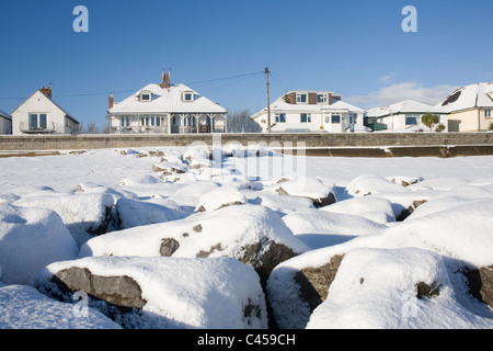 Newton, Porthcawl, DI MID GLAMORGAN, GALLES, Beach Road case con coperta di neve rocce in primo piano Foto Stock