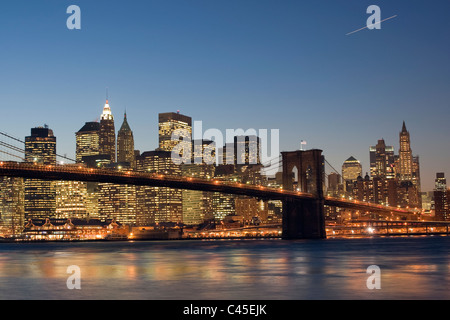 Ponte di Brooklyn e la parte inferiore dello skyline di Manhattan attraverso il Fiume Hudson al crepuscolo. Foto Stock