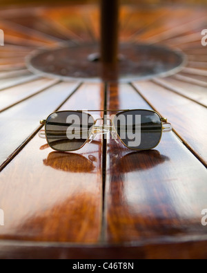 Un paio di occhiali da sole aviatore sedersi su un tavolo di legno Foto Stock