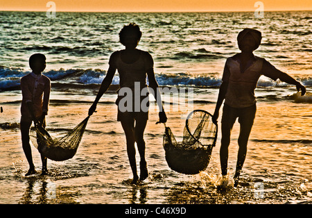 I pescatori al tramonto sulla spiaggia di Calva in Goa, India Foto Stock