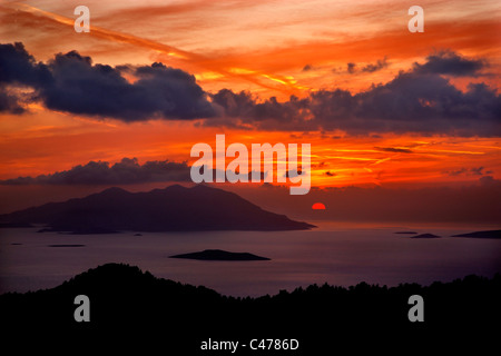 Tramonto foto da sudovest Rhodes, vicino al villaggio di Kritinia. La grande isola in background è di Chalki. Dodecanneso, Grecia Foto Stock