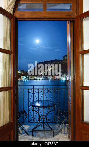 Vista notturna del pittoresco villaggio di Kastellorizo (o 'Meghisti') isola, attraverso la porta di una stanza di albergo, Grecia Foto Stock
