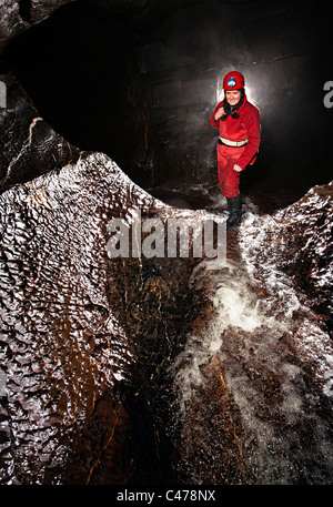 Donna speleologo in grotta passaggio con flusso Ogof Ffynnon Ddu Wales UK Foto Stock