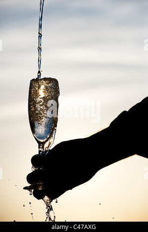 L'acqua versata in un flute da champagne. Silhouette Foto Stock