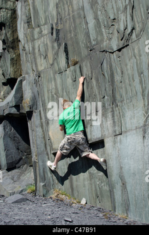 L'uomo bouldering in Welsh Slate nel combattere la roccia, Watford Gap, Twll Mawr, Galles del Nord, Regno Unito Foto Stock