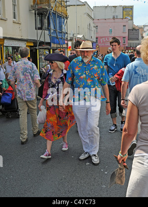 Coppia matura camminando mano nella mano indossando abiti colorati a Kemptown Carnevale a Brighton Regno Unito Foto Stock