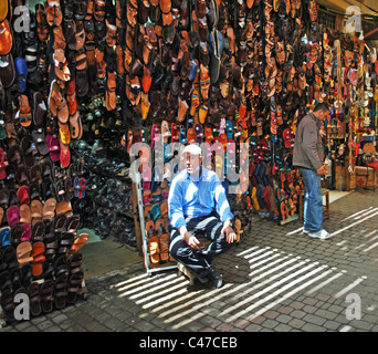 L'uomo la vendita di scarpe in un souk di Marrakech, Marocco Foto Stock