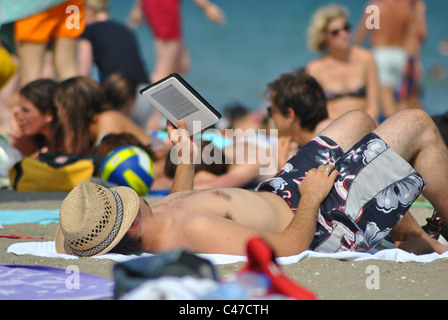 Uomo di lettura con un Kindle su una spiaggia in Italia Foto Stock