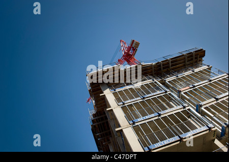 Un edificio in costruzione da parte della società Heyrod, girato con una gru nei confronti di un blu limpido cielo privo di nuvole. Foto Stock