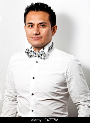 Mezza lunghezza Ritratto di un uomo latino che indossa una camicia bianca e un bow tie, contro uno sfondo bianco, London, England, Regno Unito Foto Stock