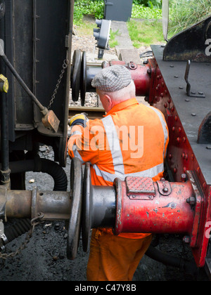 Un lavoratore su metà Hants linea ferroviaria collega i sistemi di due carrelli mentre a Leamington Spa stazione sulla linea di crescione. Foto Stock