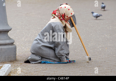 Una vecchia donna mendicando elemosina in strada Foto Stock