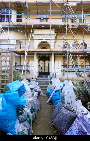 Proprietà sotto lavori di rinnovo con i ponteggi e i rifiuti nel giardino anteriore Foto Stock