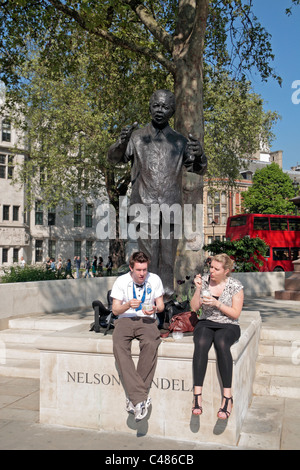 Un paio di mangiare il loro pranzo di fronte alla statua di Nelson Mandela in piazza del Parlamento, Londra. Foto Stock