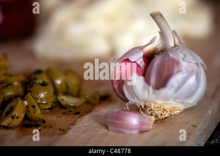 Spicchio di aglio su un tagliere accanto ad alcune olive a fette Foto Stock